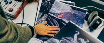 Une main qui touche des illustrations, une sonsole sonore sur la gauche