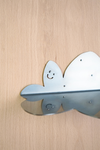 Une forme de métal illustrant un nuage avec un sourire, vissé sur du bois