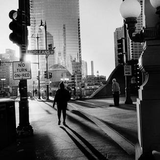 Une personne marche vers une rue du centre ville devant une lumière à contre-jour