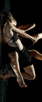 Une danseuse au sol contre son reflet, donnant l'impression de deux corps entremêlés