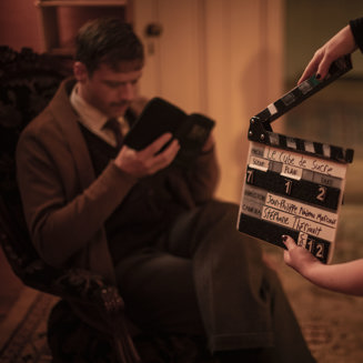 Une personne regarde son carnet derrière une palette de tournage de cinéma