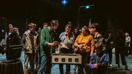 Deux personnes attroupées autour d'un dispositif technilogique musical