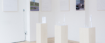 Une exposition d'items prototypiques sur trois petites colones rectangulaires blanches