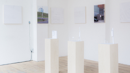 Une exposition d'items prototypiques sur trois petites colones rectangulaires blanches