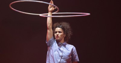 Une femme avec une main en l'air faisant tourner deux cerceaux 
