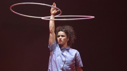 Une femme avec une main en l'air faisant tourner deux cerceaux 