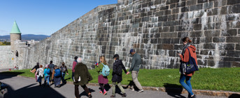 Une dizaine de personnes suivent un parcours pédestre le long de remparts en pierres