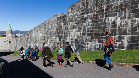 Une dizaine de personnes suivent un parcours pédestre le long de remparts en pierres