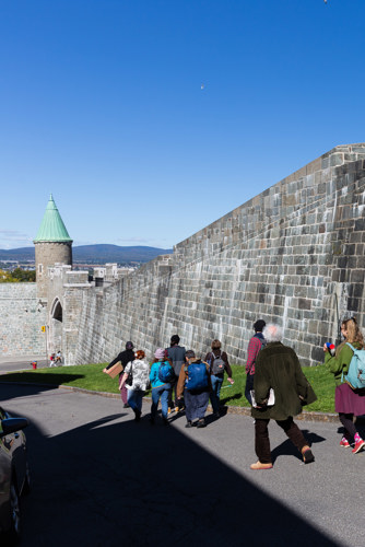 Une dizaine de personnes suivent un parcours pédestre le long de remparts en pierres