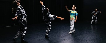 Chorégraphie de danse avec trois femmes en costumes noirs et blancs et une femme en vêtements colorés