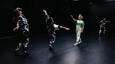 Chorégraphie de danse avec trois femmes en costumes noirs et blancs et une femme en vêtements colorés